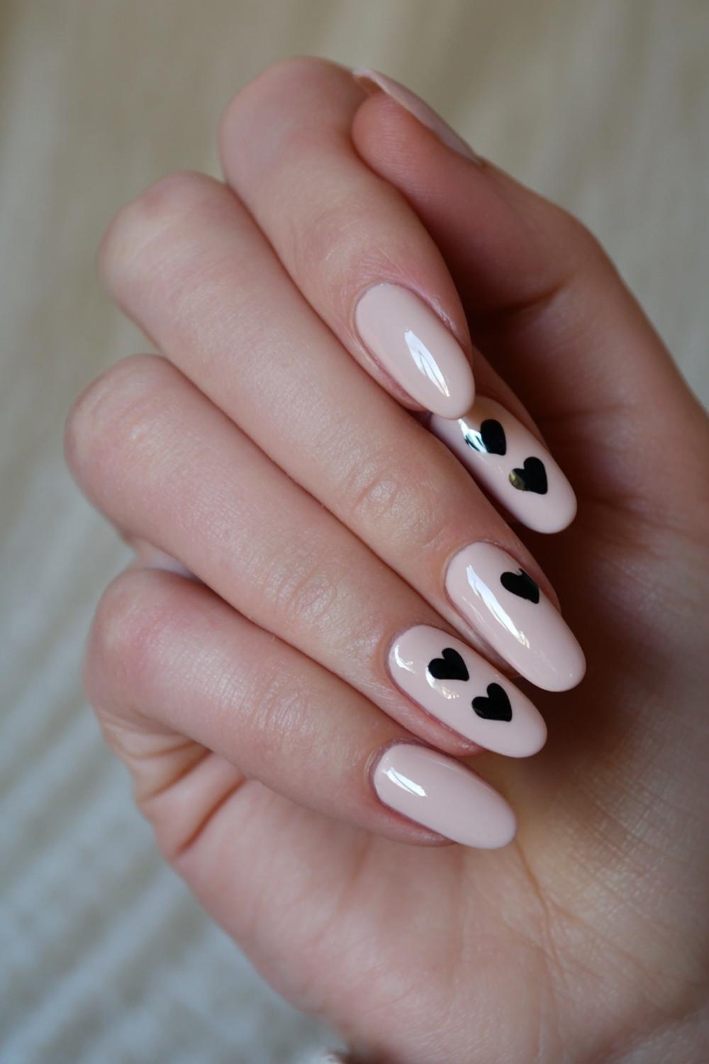 5. Valentines nails met nude basis en zwarte hartaccenten